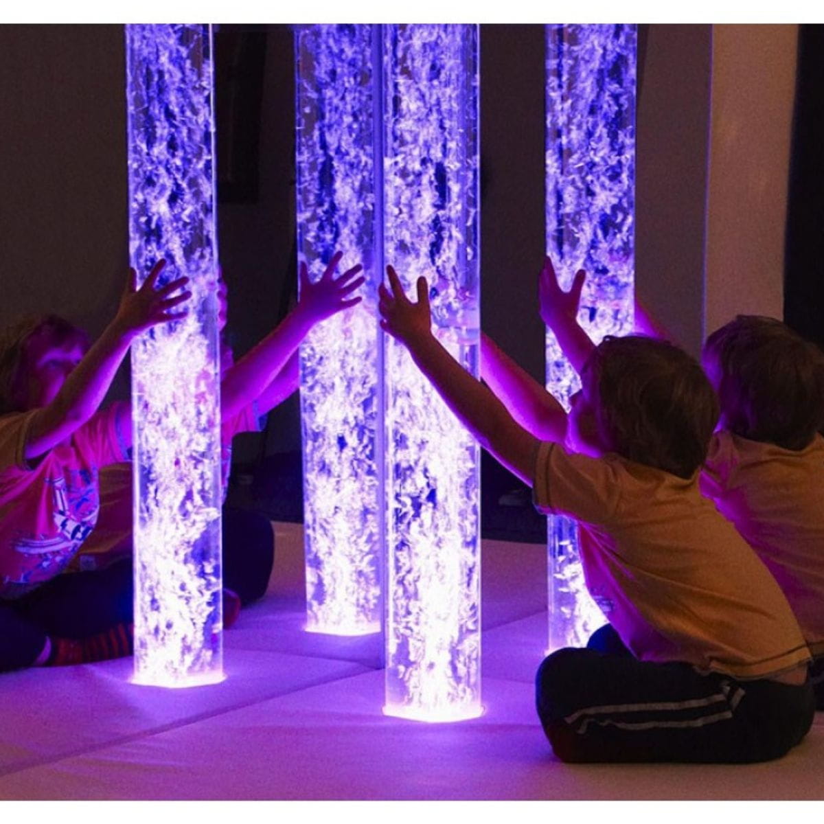 Calming Sensory Room Package with Kid sitting on platform playing with purple bubble tube