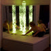Child sitting on platform of Interactive Bubble Tube Corner Set and changing colors with color pad