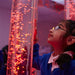 Child with hand on Calming LED Sensory Bubble Tube and staring at the fish inside it 