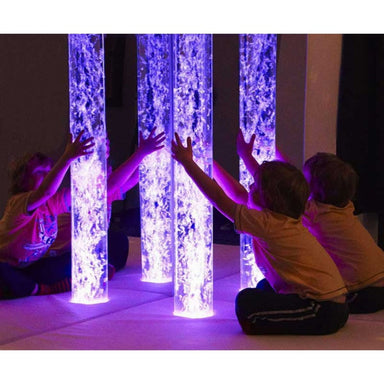Child with hands around the lit up Calming Bubble Tube