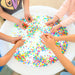 Eight hands playing with beads in the center of the Light up sensory table