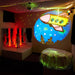 Experia Calming Sensory Room Package with Kid standing on platform next to red bubble tube with green fiber optic lights and rocket on projector slide