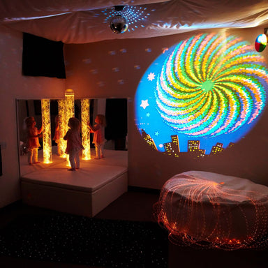 Experia Calming Sensory Room Package with kid on platform looking at orange bubble tube and projector showing stars 