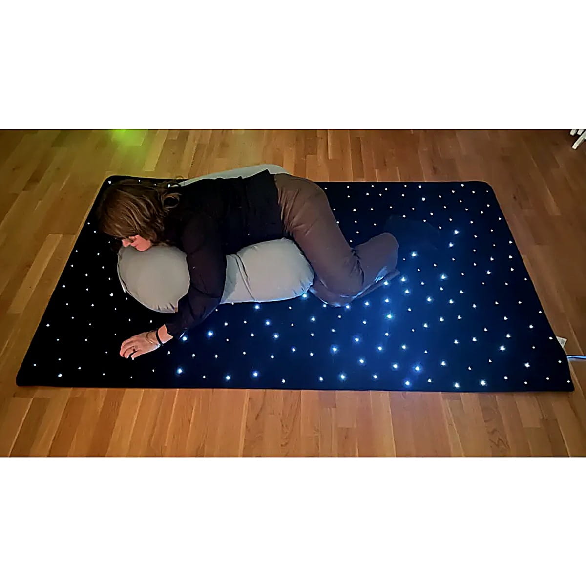 Girl laying on the TFH Fiber Optic Starfield Carpet with a pillow