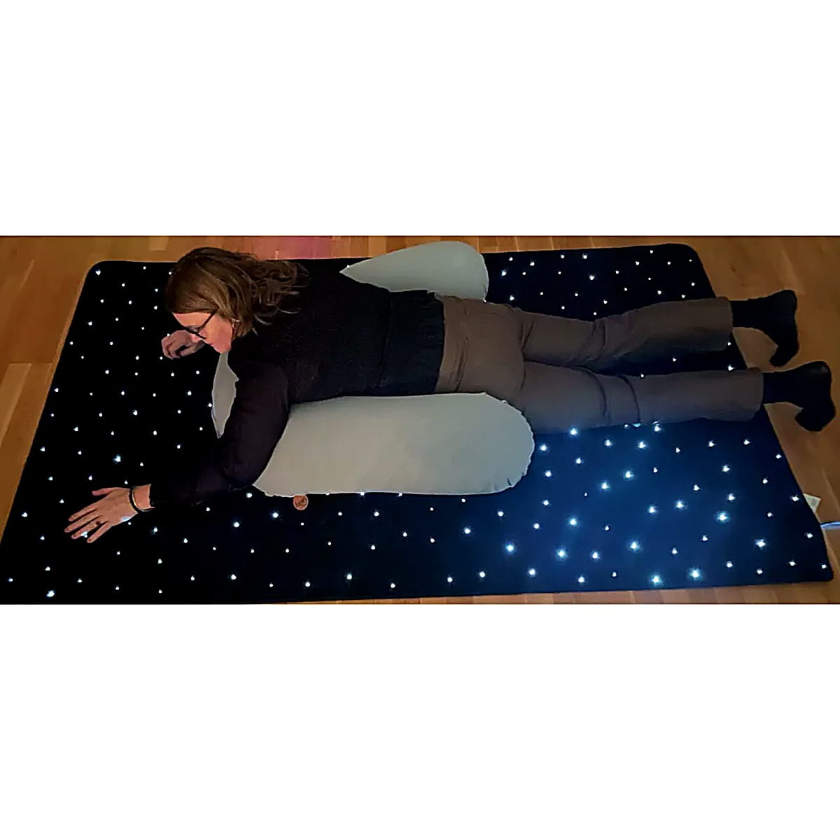 Girl laying on the TFH LED sensory carpet and rubbing it with her hand