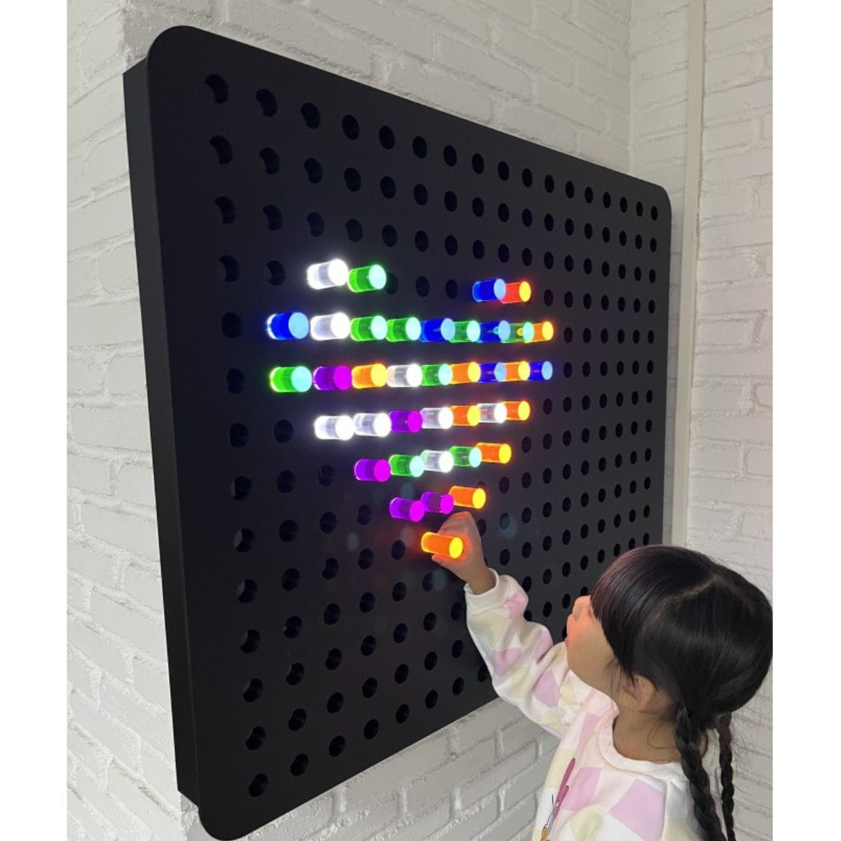 Girl playing with the PixelPop Interactive Sensory Light Wall Panel and making a heart