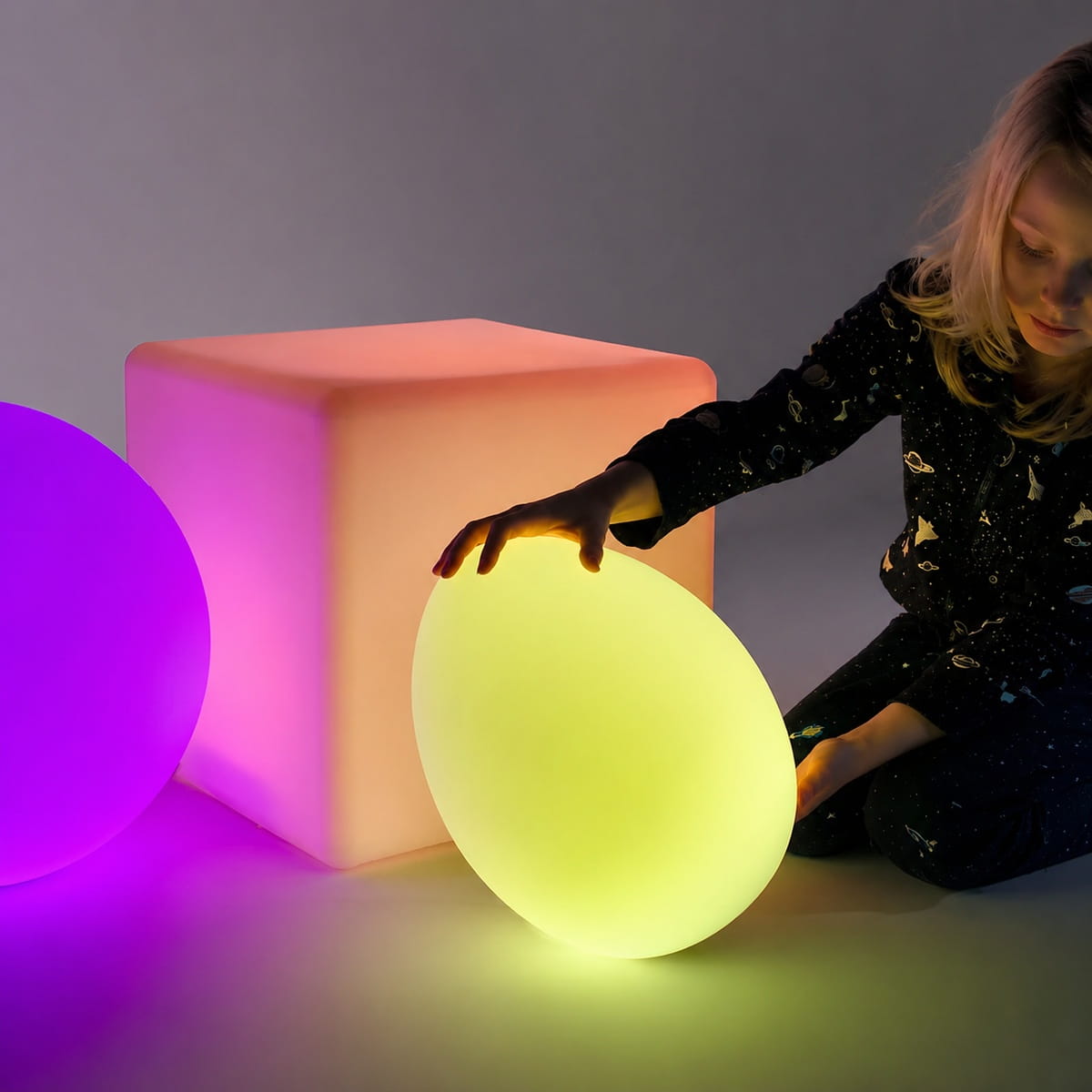 Girl with LED Sensory Egg in hands and the ball and square next to her