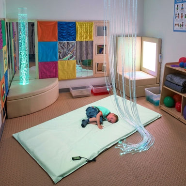 Kid laying on the Vibrating Sensory Mat in a sensory room