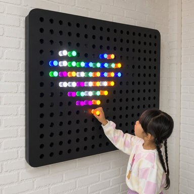 Kid playing with the PixelPop Interactive Sensory Light Wall Panel and making a heart