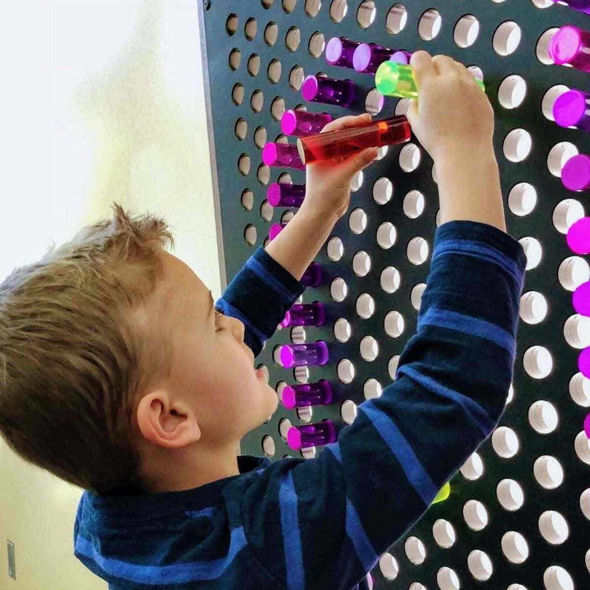 Kid putting two LitePins into the LiteZilla Lite Brite Wall
