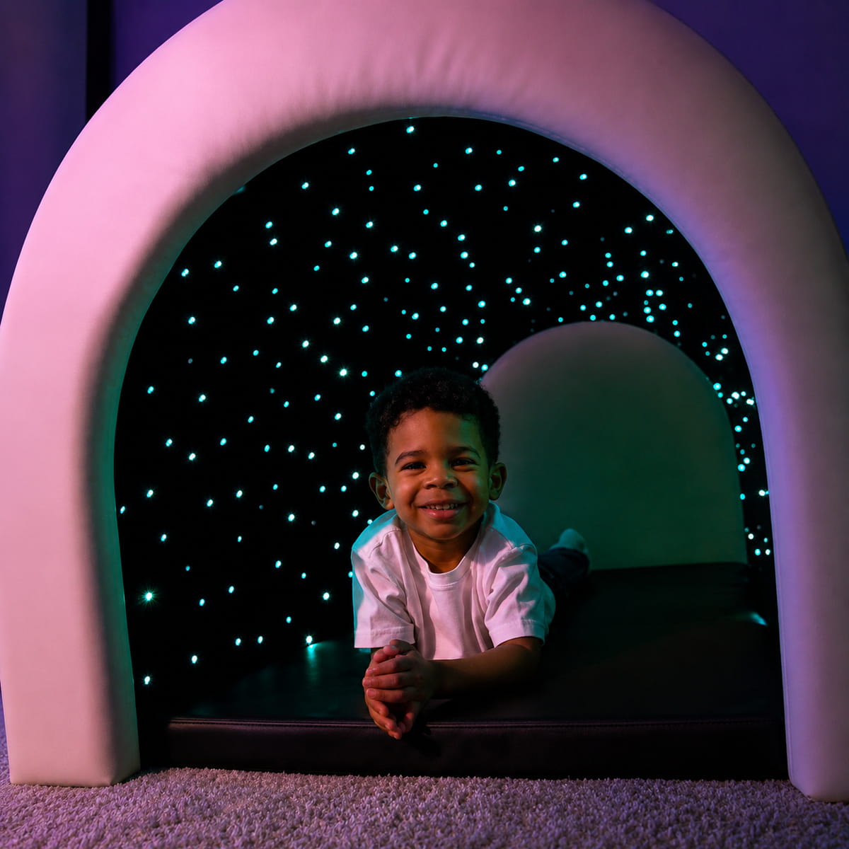 Kid smiling while laying in the Tranquility Fiber Optic Sensory Tunnel