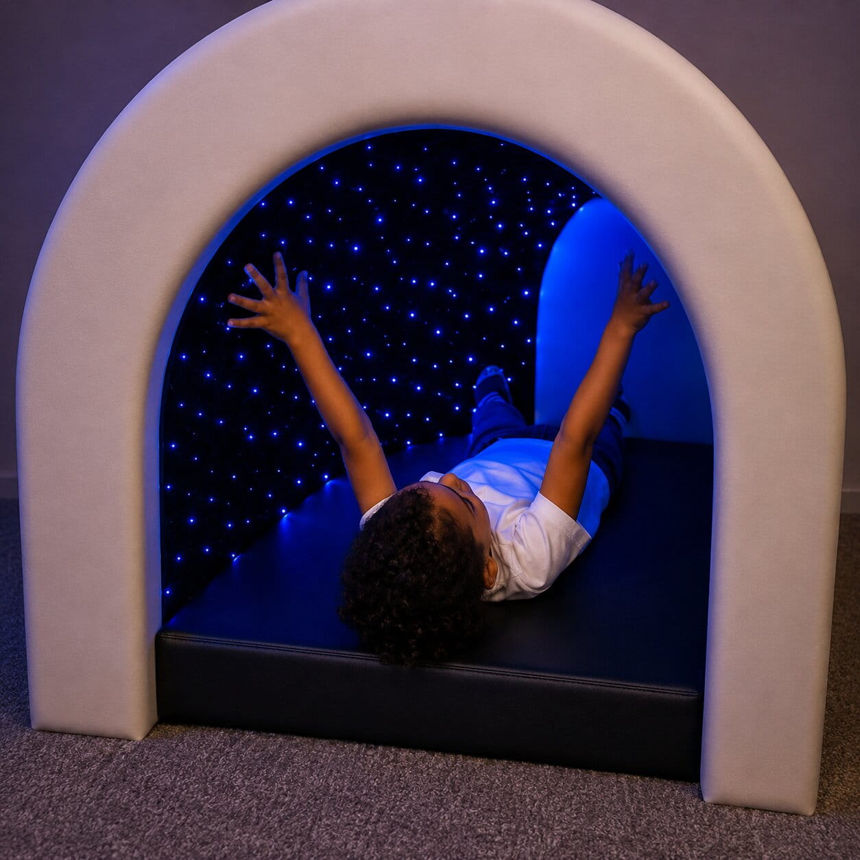 Kid smiling while laying in the Tranquility Fiber Optic Sensory Tunnel looking up at the lights