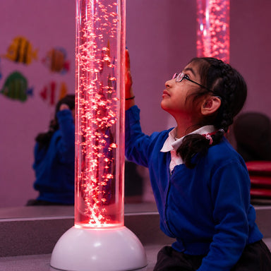 Kid with hand on Calming LED Sensory Bubble Tube looking into it