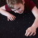 Kid laying on the Experia USA LED Fiber Optic Carpet playing with the lights