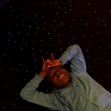 Kid laying on the LED Fiber Optic Star Carpet with a calming look