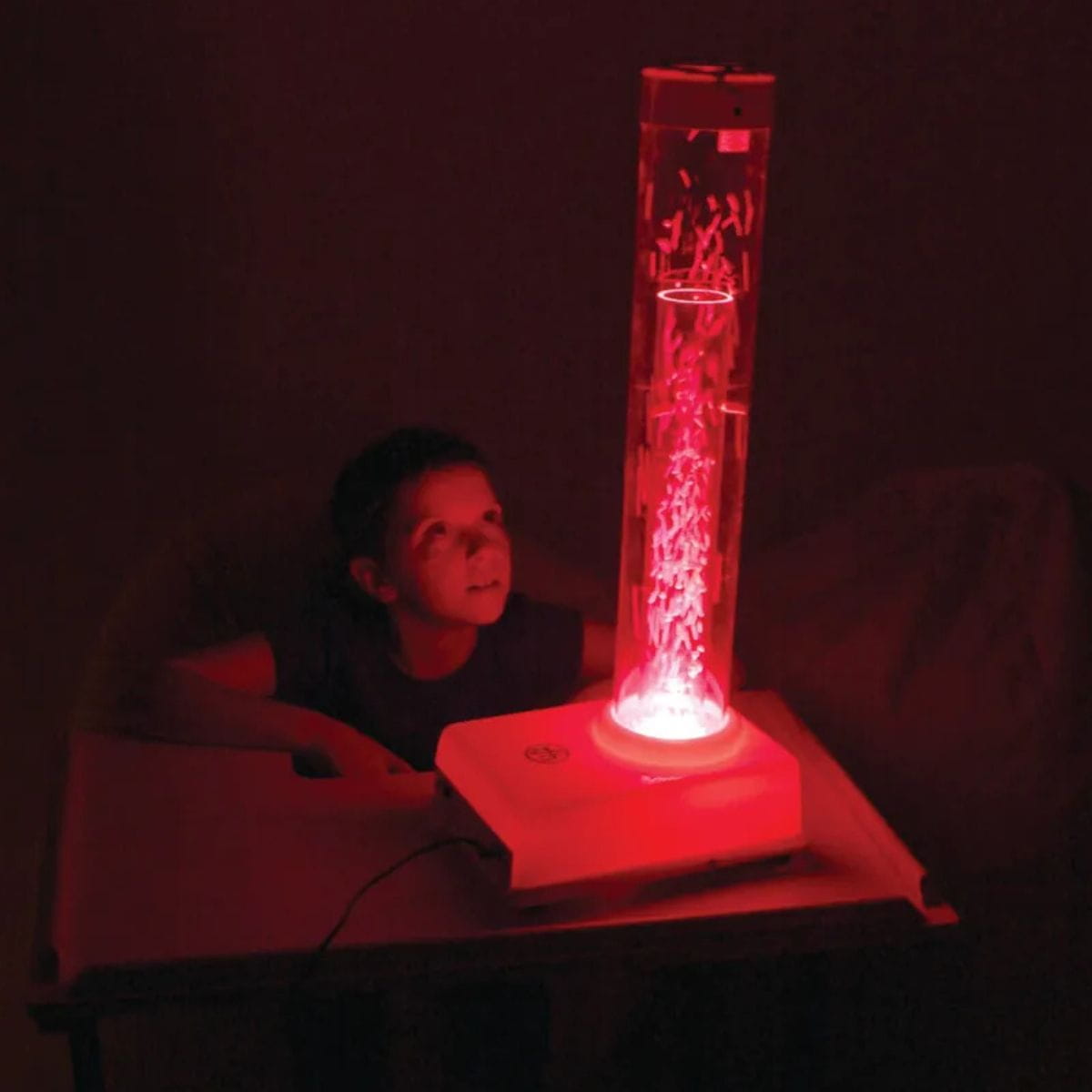 Kid looking up at the bright red TFH Tabletop Hurricane Tube in the dark