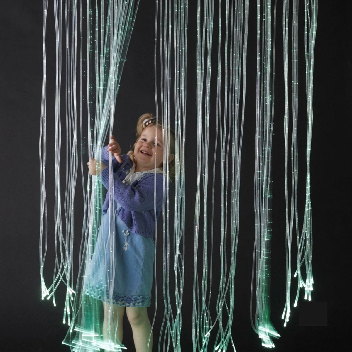 Kid playing with the Fiber Optic Curtain Lights mounted from the ceiling
