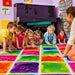 Kids and teacher next to rows of Large Square Liquid Sensory Floor Tiles