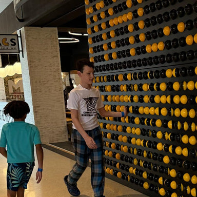 Kids flipping the black and yellow balls on the LiteZilla Spinfinity Wall