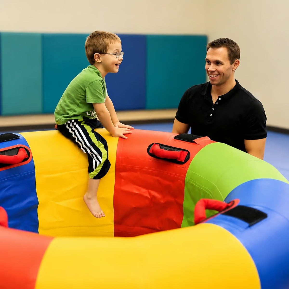 Kid sitting on edge of Sensory Fitness Wheel with adult near