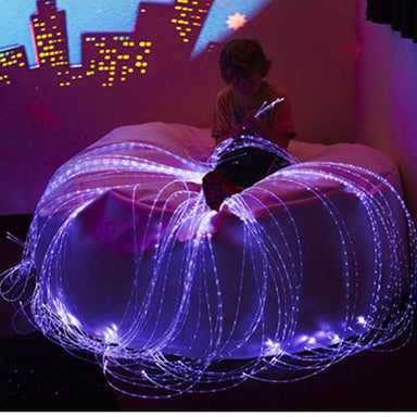 Kid sitting on the Softie Sensory Bean Bag with the LED Fiber Optic lights in his hand