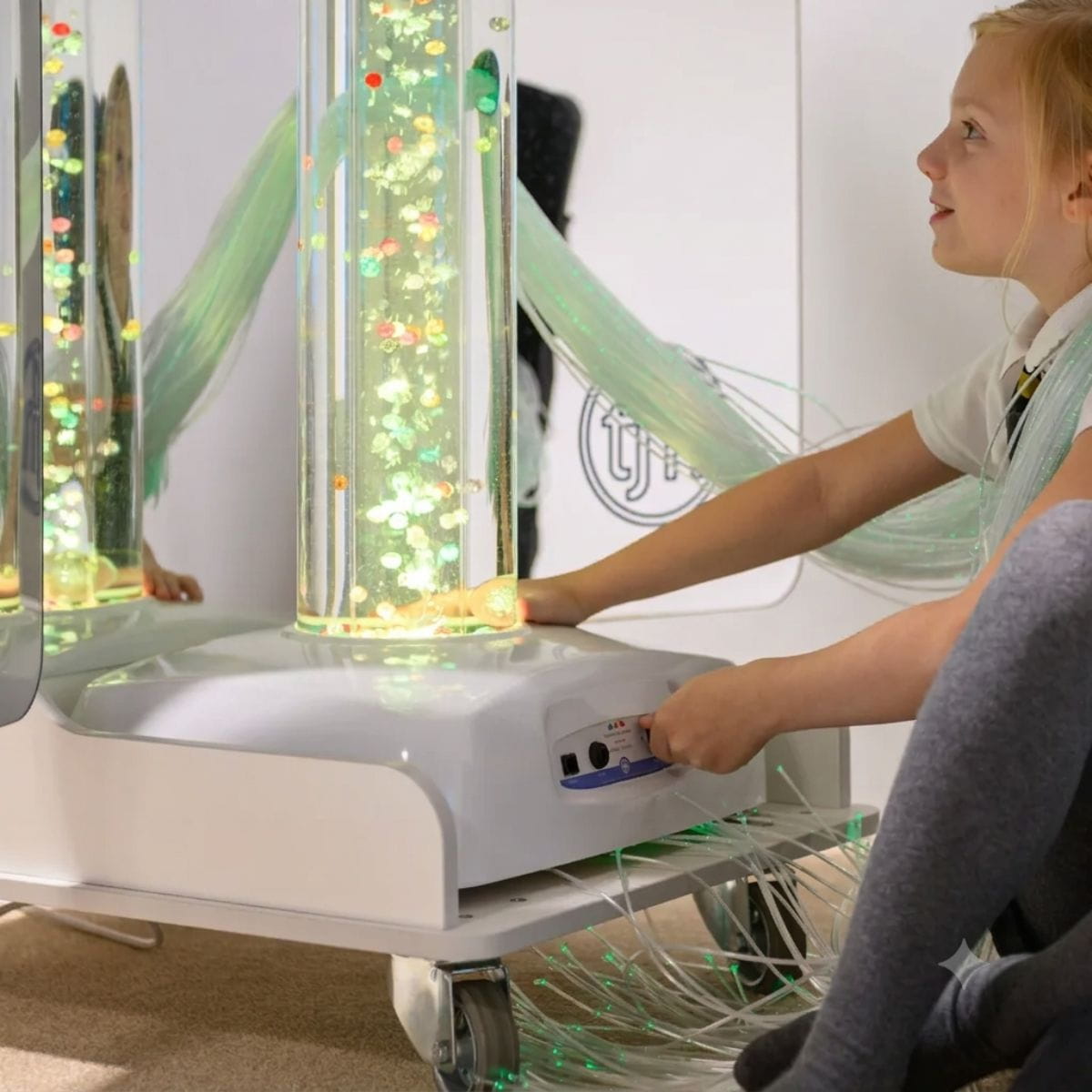 Kid smiling and adjusting the bubble tube setting on the Vecta Deluxe Mobile Sensory Cart