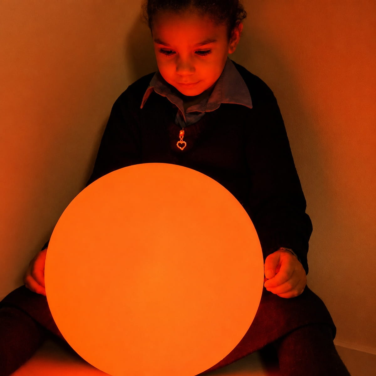 Kid stares into the orange LED Sensory Ball