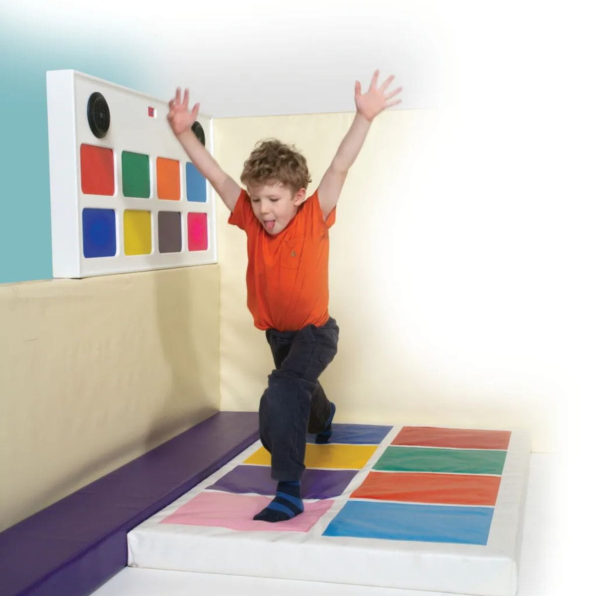 Kid with both hands up and feet on two squares of Interactive Music Squares Sensory Panel