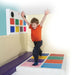 Kid with both hands up and feet on two squares of Interactive Music Squares Sensory Panel