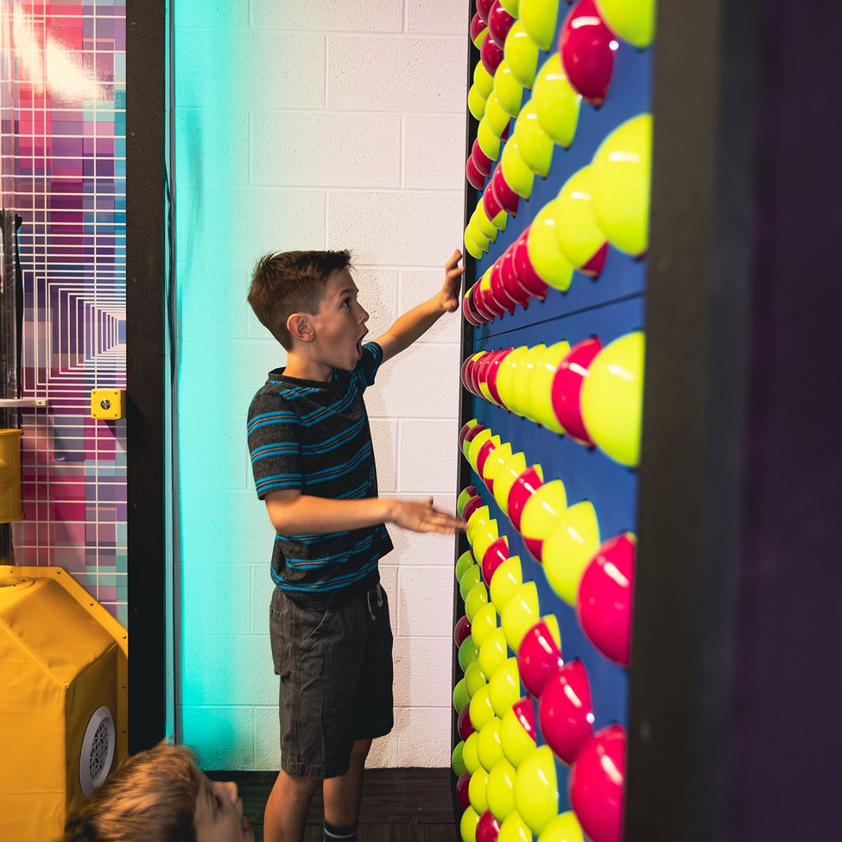 Kid with excitement on his face playing with the LiteZilla Spinfinity Wall