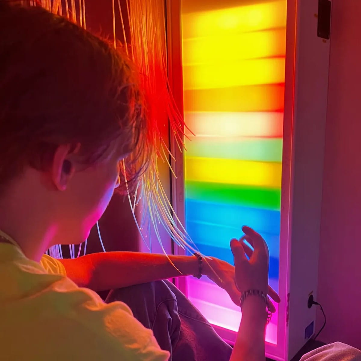 Kid with hands up next to the Sensory Ladder Lights Fiber Optic Color Glow