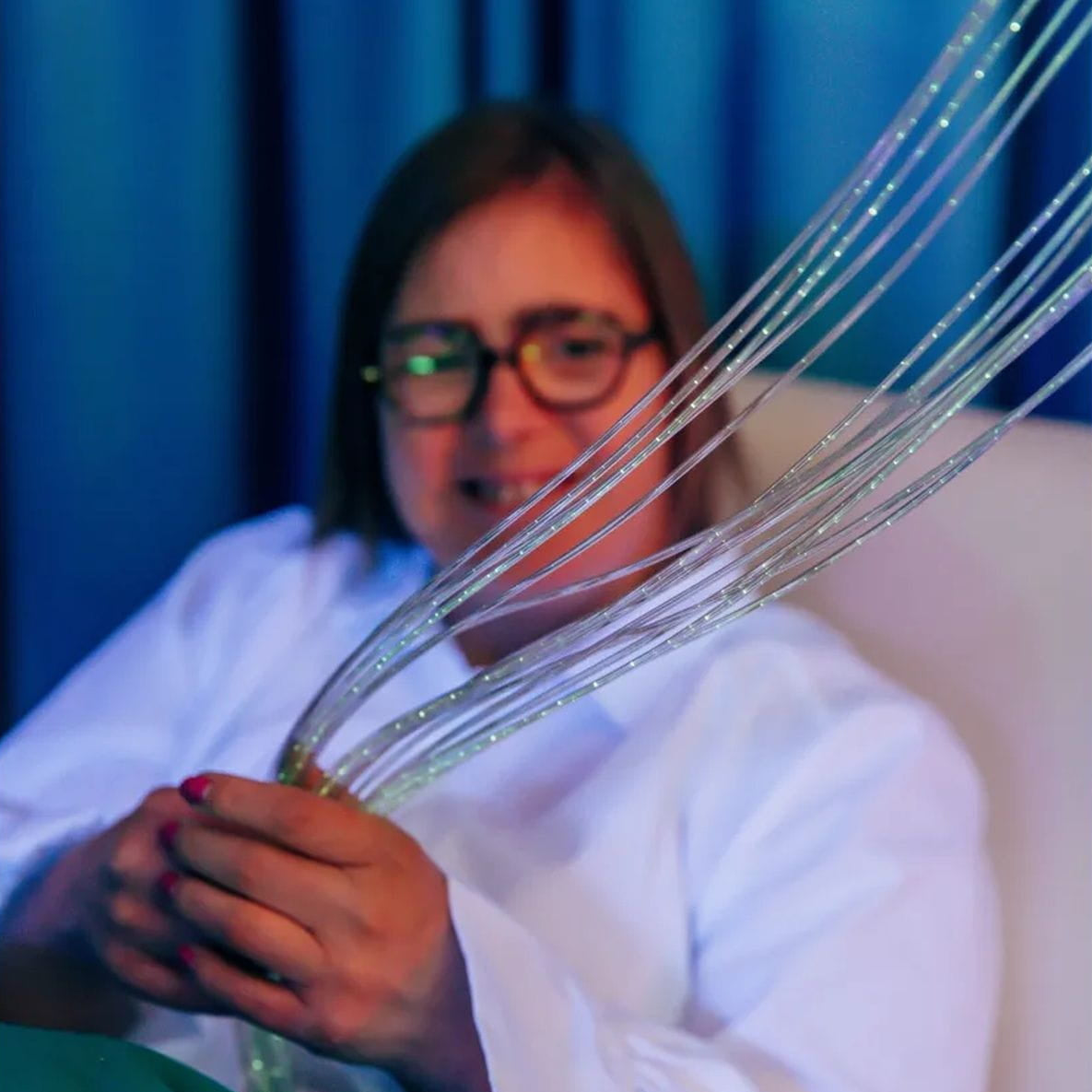 Lady playing with the fiber optic sensory light curtain strands