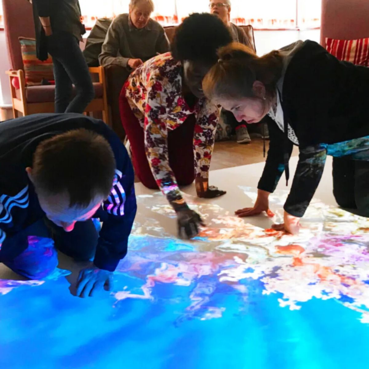 People looking closer at the Budii Interactive Projector image on the floor