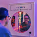 Person smiling into the LED Infinity Tunnel Mirror with red lights