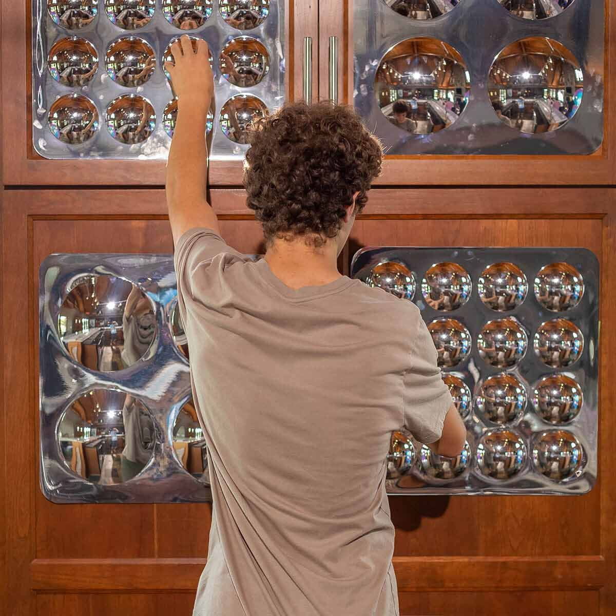 Person touching Litezilla Sensory Bubble Mirror Panels with their hands that are attached to the wall
