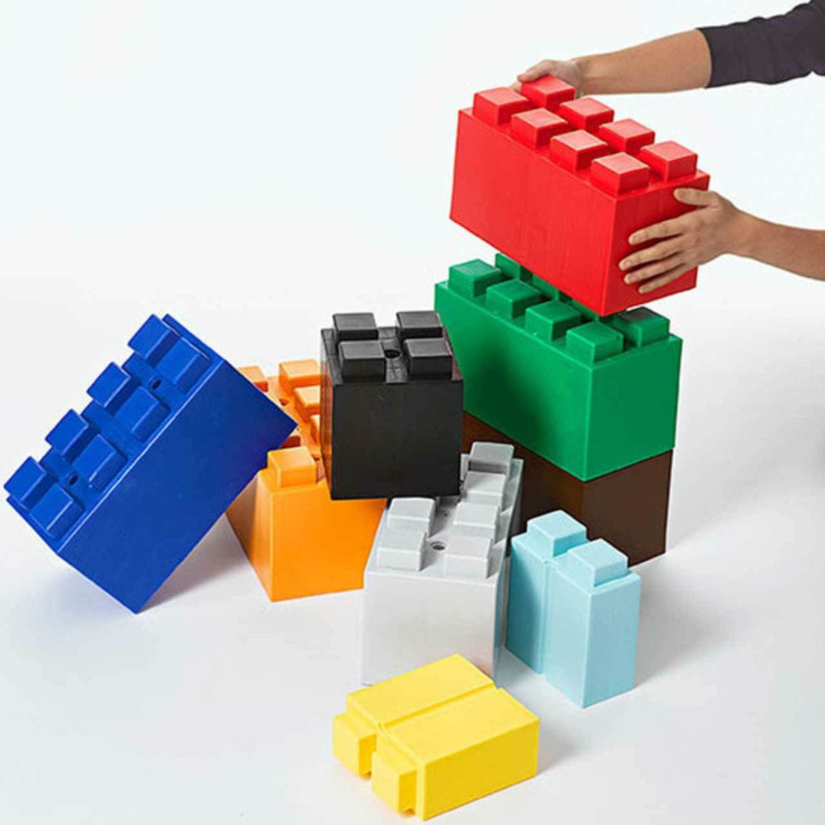 Someone putting one EverBlock Modular Building Blocks on another with more surrounding them in different colors