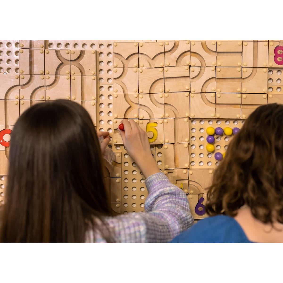 Two girls playing the game Magnet Maze Builder on the Kidworx Interactive Game Board