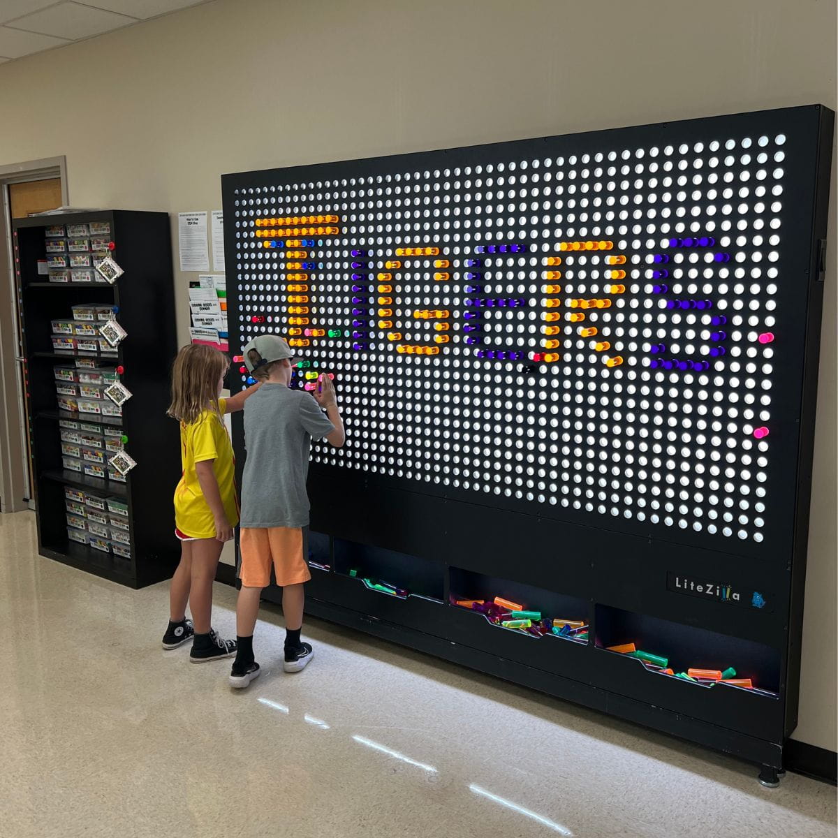 Two kids making a design with Tigers spelled out on the 8x6 LiteZilla Giant Lite Brite Wall
