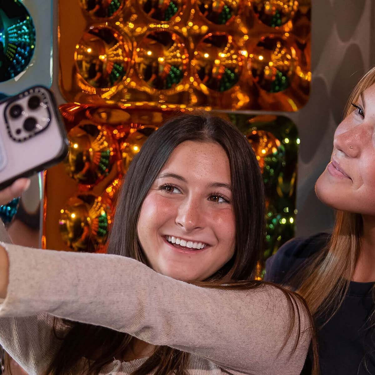 Two girls taking a selfie with Sensory Bubble Mirror Panels in the background
