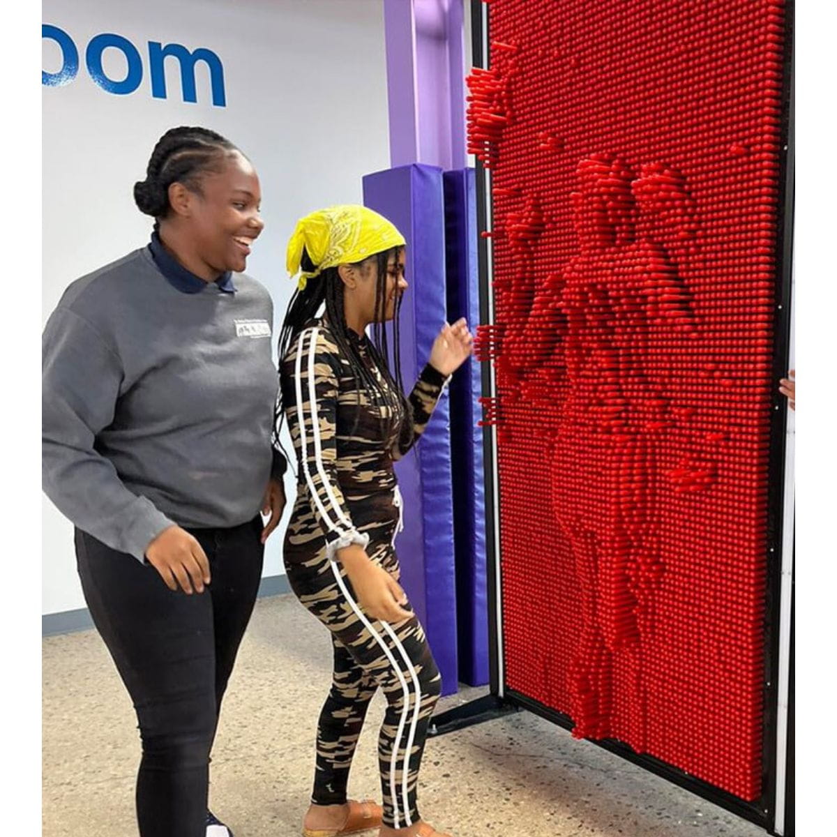 Two kids making impressions of themselves on the LiteZilla Clone Box Pin Wall