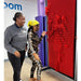 Two kids making impressions of themselves on the LiteZilla Clone Box Pin Wall