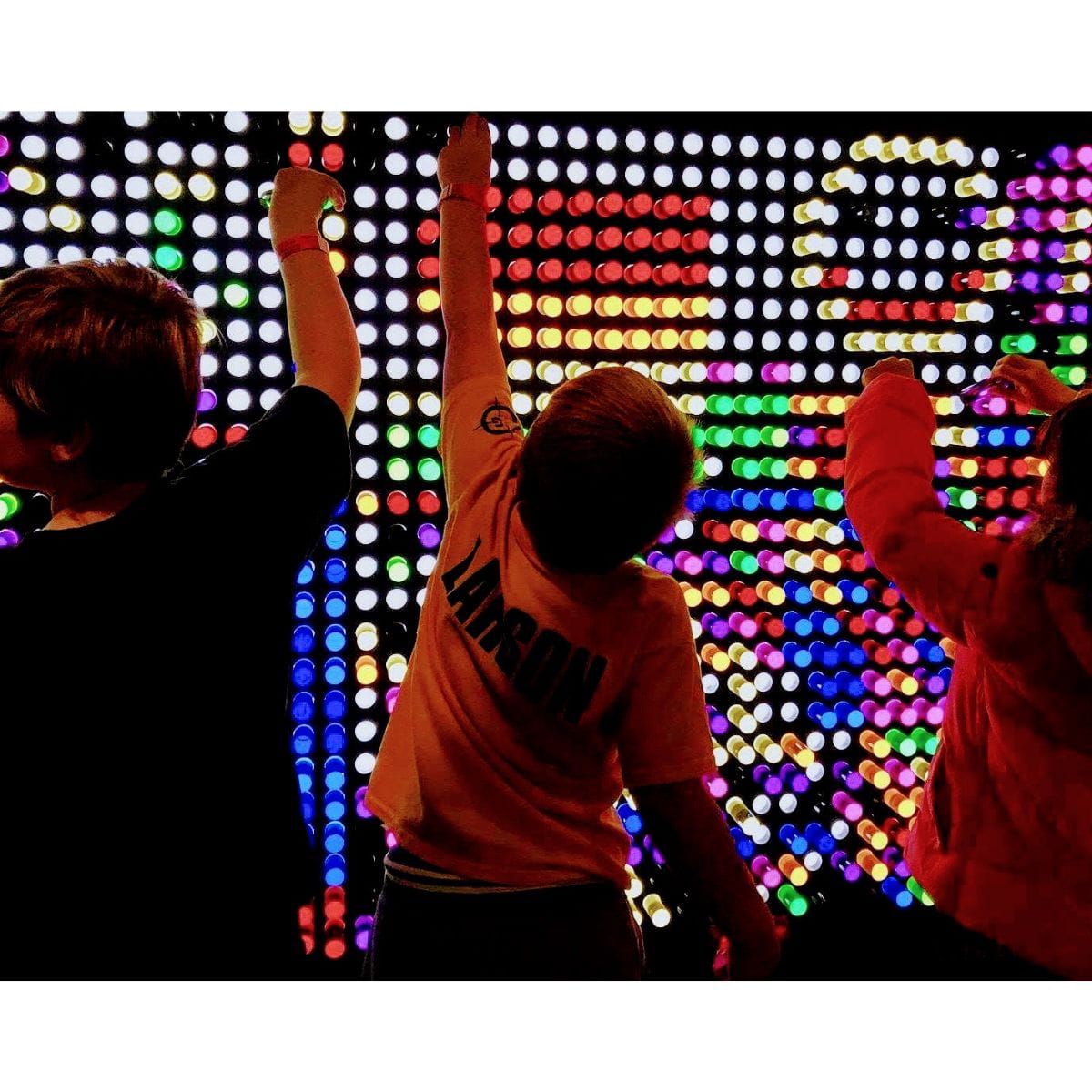 three kids playing on the LiteZilla Interactive Light Wall making designs